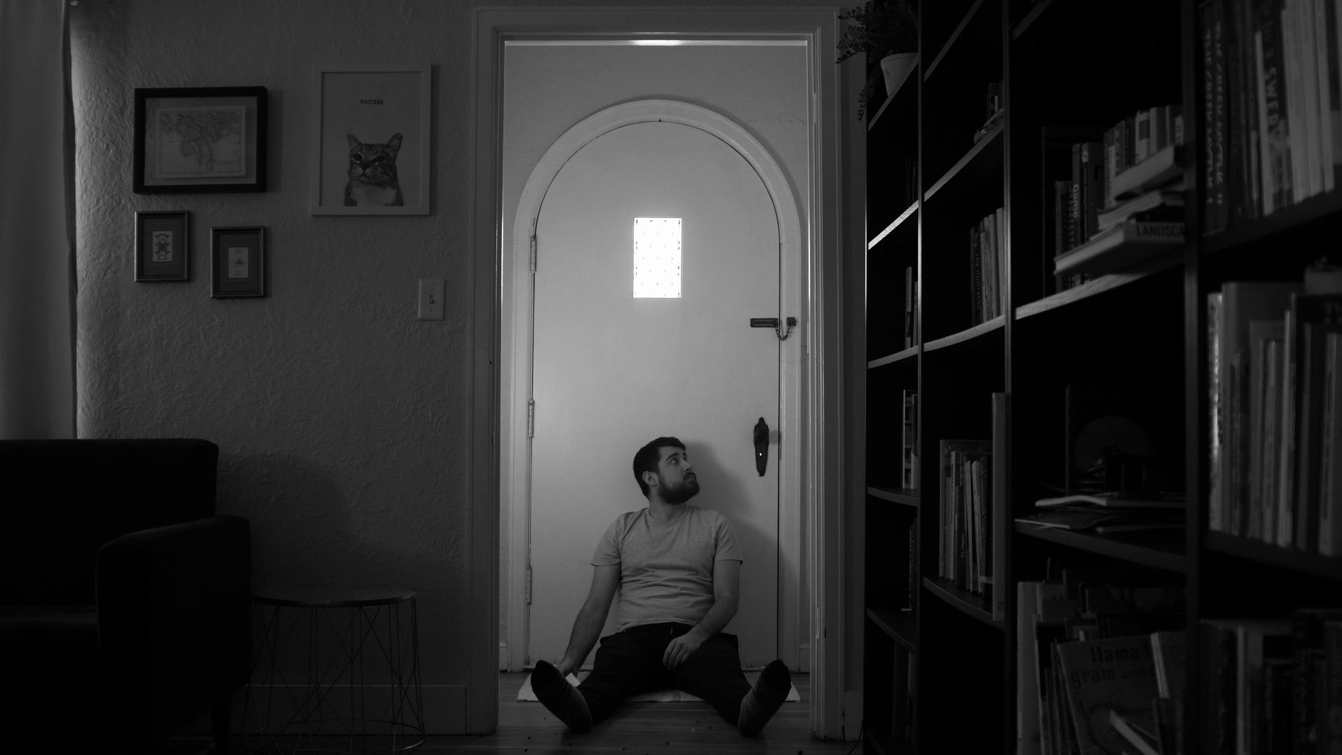 A shot of a man sitting in front of a doorway with light spilling in through the door window